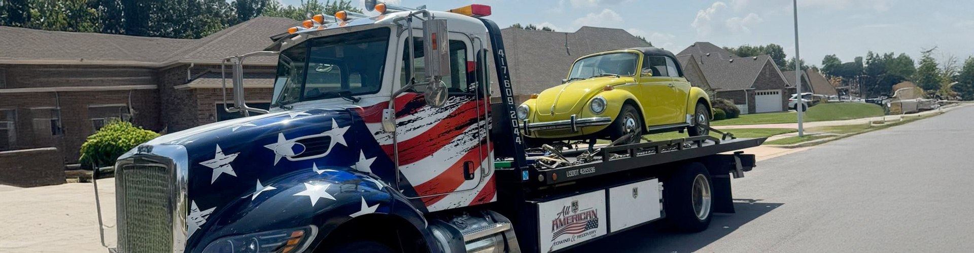 A flag-painted truck represents towing service provided by All-American Towing & Recovery